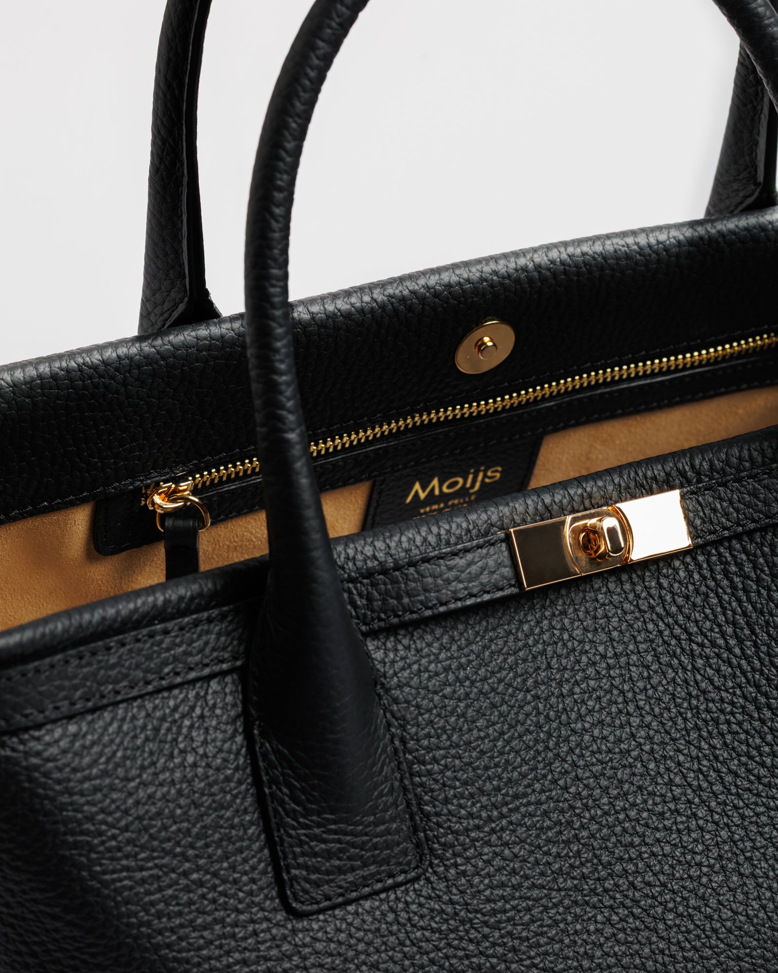 Dettaglio della chiusura dorata e della pelle di vitello nera della borsa Moijs
